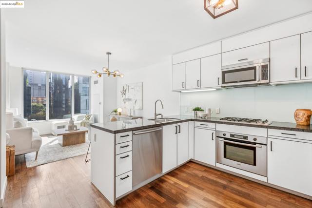 Kitchen with a peninsula, appliances with stainless steel finishes, a chandelier, dark wood finished floors, and open floor plan