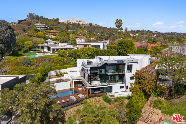 12002 Benmore Terrace Los Angeles, California Quintessential California living at this spectacularly stunning and private modern. Breathtaking views span the Pacific Ocean, Catalina Island, Downtown LA and the Getty Center. An entertainers paradise, this exquisite property blends indoor and outdoor living spaces which include an outdoor BBQ, wet bar, spacious multi-level decks, a sparkling zero edge pool and spa, various movie screening options, a sports court, and a capacious rooftop lounge overlooking canyons and coastal views. Southwest facing movable wall windows flood natural light and blow gentle breezes into the sleek, minimalist space. 4 en-suite bedrooms w/ retractable shades for addt'l privacy are spaced out on the top level with art gallery lighting in hallway. Retreat to a tranquil primary room and luxurious bath with oceanic and canyon views. Elevated formal dining and entertaining on mid-level along with an expansive kitchen equipped with European cabinetry, Miele built-in appliances, and temperature-controlled wine room. The pool deck level opens to a lounge area suited for R&R with indoor entertainment, a soundproof home theatre room, and two guest bedrooms that can also be used as a home gym and WFH office. Whole home automation controls, security, temperature, lighting, outdoor areas, speakers, and home theatre. Shops, restaurants and cafes are just down the hill.