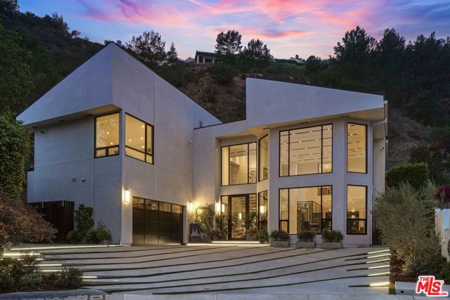 1463 Floresta Place Pacific Palisades, California Impeccably designed by award-winning architect Michele Saee, this ultra-contemporary smart home rests upon a rare 2.27-acre parcel of land at the top of a cul-de-sac in Pacific Palisades with expansive hillside and city views. Showcasing functional living spaces and a fresh art gallery-style design, the home is replete with light porcelain floors and walls of energy-efficient windows that fill each space with incredible natural light. Through the foyer, the great room instantly captivates with two-story ceilings, flowing seamlessly into a flex living space and dining area with a 2,200-bottle wine cellar. Also on the main level is the gourmet kitchen, complete with custom Italian lacquered cabinetry, Gaggeneau appliances and a 16' island with quartz counters. The home features four en suite bedrooms, including the luxe primary suite with 20' closet, resort-like bath with Toto Neorest and tranquil balcony, and comes fully equipped with a Crestron system, solar panels, backup 22 kW Generac generator, elevator, and 2-car garage with epoxy floor. Just outside lies a lush hillside oasis with a built-in BBQ, lounge areas, fruit trees, vegetable garden, firepit, and pool and spa for ultimate relaxation and entertainment. Contemporary in design yet comfortable by nature, this home sets an entirely new benchmark for future-thinking design in Pacific Palisades.