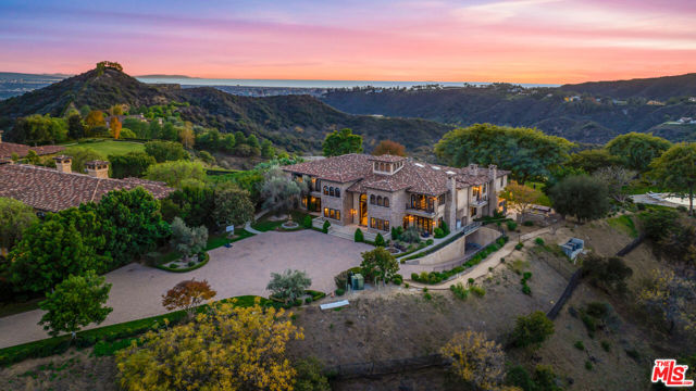 World-Class Mediterranean Villa situated on over 3.1 acres in the ultra-exclusive 24-hour guard-gated community of Beverly Ridge. Perched on a promontory accessed via a long, private drive, this one-of-a-kind estate offers grand scale living with elegant proportions and holds infinite possibilities for entertaining and amazing year-round indoor-outdoor living. As you enter, be greeted by a grand two-story foyer and a sweeping double staircase. The home has been designed to maximize natural light and features a large living room with bar, office, gourmet kitchen, breakfast room, family room, luxurious dining room with walk-in wine display/cellar, and private theater. There is also an apx. 3,600 sq.ft. subterranean garage offering parking for seven cars, an informal gym/playroom, an elevator, and two maid's rooms. The primary suite boasts spa-like dual bathrooms, vast walk-in closets, and two private office suites. All guest bedrooms are en-suite, with beautiful baths and closets, and offer stunning views. Warming floors complete all the stone bathrooms upstairs. The fabulous gourmet kitchen features two refrigerators, a built-in coffee maker, a steam oven and multi-use microwave, four ovens, two dishwashers and a warming drawer. All water is potable. The park-like grounds are complemented by a sprawling covered patio, outdoor fire pit, glamorous pool and spa, and breathtaking 360 views that span all the way from the mountains to the ocean.