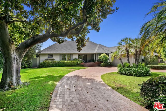 13838 W Sunset Boulevard Pacific Palisades, California Magical, Meticulous and Mesmerizing! Nestled in the elite Palisades Riviera enclave that is found only by winding through historically prestigious Sunset Boulevard, this charming traditionally built home boasts comfort and quality in a serene setting with pastoral scenes of magical, saturated green gardens with spots of color, shaded by mature trees. A large and gracious lot with circular brick driveway behind privacy walls of thick hedges provides for impressive street presence and estate-like feel. Paired with warm, inviting entry and living areas with honey-colored hardwood floors and views into lush greenery and well-appointed covered patio space exude an overall ambiance of quiet elegance and serene comfort. Spacious rooms convince with intricate design details such as white brick-mantled fireplaces and paneled walls. The traditional primary bedroom suite features glowing natural light with ensuite vanity/dressing area. A thoughtfully designed kitchen invites for entertaining as well as everyday living and relaxing. The ideal flow from kitchen and breakfast nook to grand dining functions serves as well for formal as it does casual living, all with views of meticulously kept gardens. A very gracious, beautiful, timeless and estate-like home offering the most scenic and prestigious of Palisades neighborhoods and the ultimate in privacy while in close proximity to beach/hiking/biking and everything Palisades Village!