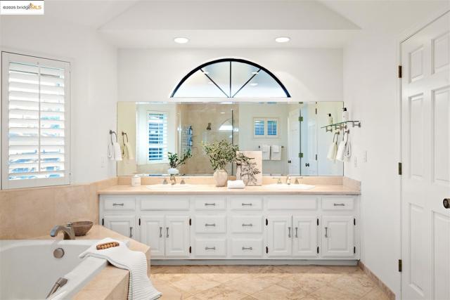 Full bath with double vanity, a stall shower, a bath, and recessed lighting