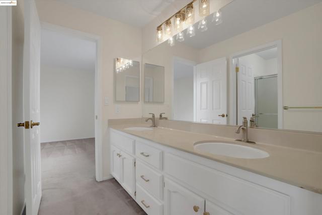 Bathroom featuring double vanity, light carpet, and a shower with shower door