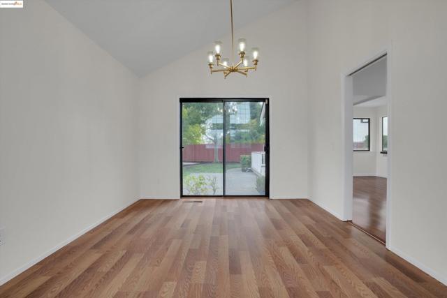 Unfurnished dining area featuring high vaulted ceiling, light wood-style floors, and a chandelier