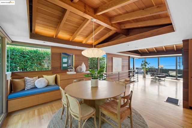Dining space with wood ceiling, plenty of natural light, light wood finished floors, and wooden walls