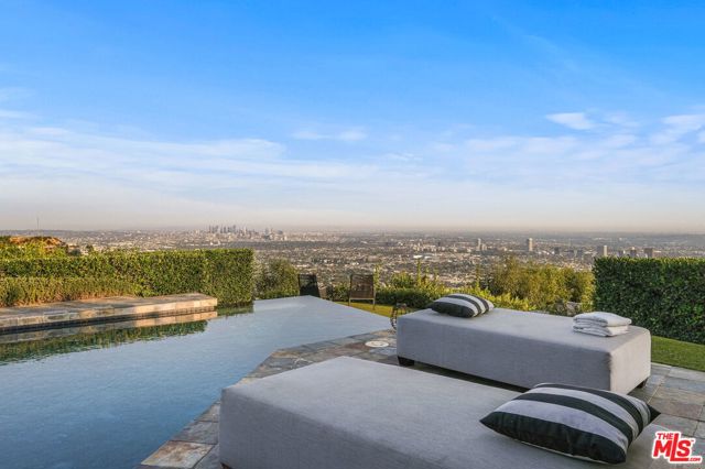 9000 Hopen Place Los Angeles, California Nestled on a small cul-de-sac off Blue Jay Way in the exclusive Bird Streets, this single-story jewel-box boasts unobstructed 180-degree jetliner views from Downtown LA to the Ocean. With an open floor plan, the living area is replete with vaulted ceilings and stunning herringbone-patterned wood floors. The recently remodeled chef's kitchen opens to the striking view with a massive center island with gorgeous marble waterfall countertops and built-in seating for 6. An impressive owner's suite opens out to the sleek infinity-edge pool, stone-tiled deck, and grassy yard with outdoor kitchen/BBQ. 2-car garage with additional private driveway spaces. With complete privacy, timeless architecture, and unparalleled views, this is a once-in-a-lifetime opportunity to own such a mesmerizing home on such a desirable parcel of land.
