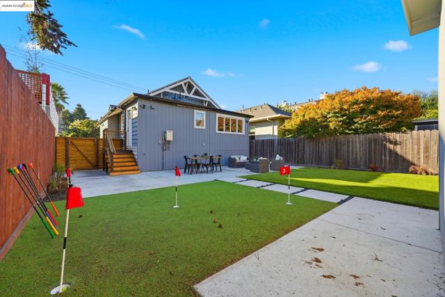 Back of house featuring a patio, an outdoor living space, a fenced backyard, a gate, and an area to practice putting
