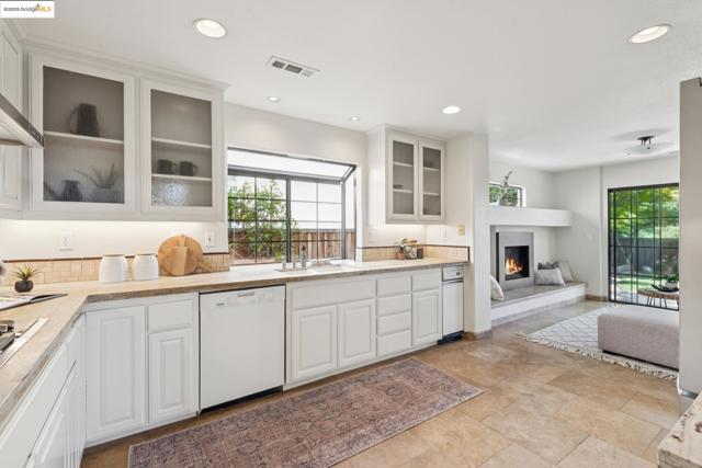 Kitchen with white cabinets, recessed lighting, dishwasher, glass insert cabinets, and a lit fireplace