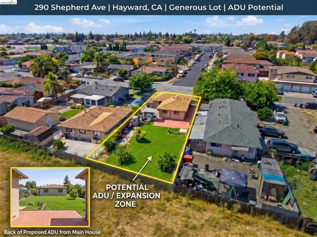 Expansive lot with a spacious grassy area, mature trees, and an existing patio