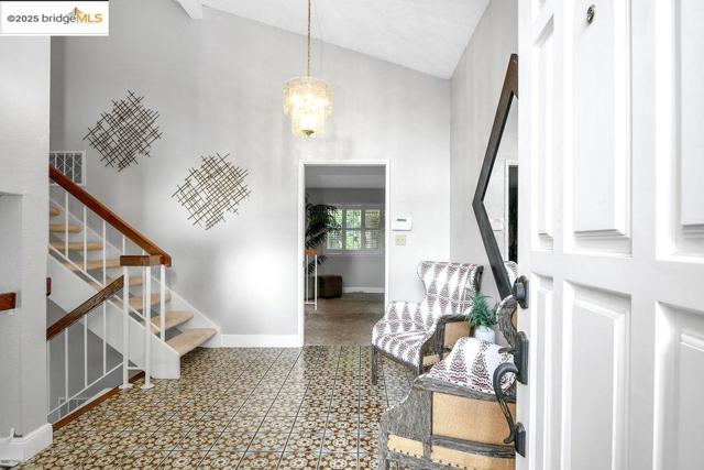 Foyer featuring stairs, high vaulted ceiling, and a chandelier