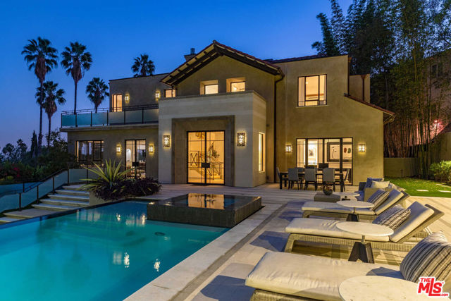 7801 Hillside Avenue Los Angeles, California This expansive contemporary-traditional estate sits on close to a half-acre lot and is located above the famed Sunset Strip, offering tranquil mountain and city views. The gated property is private with mature landscaping and updated with high-end systems including a theater and a fully equipped gym. High ceilings, arched doorways, steel-framed doors and windows, and warm finishes are offered throughout. The main floor features a chef's kitchen with high-end appliances adjacent to the dining room and opens to a cozy, yet spacious family room. The formal living room features a fireplace and leads to a billiard room and a guest suite. The upper level offers a spectacular primary suite with a sitting area, fireplace, 180-degree views, spa-like bathroom, and three additional guest bedrooms. The guesthouse is outfitted as a fabulous fitness center with a full bathroom. Truly incredible grounds perfect for entertaining, with extensive lounge areas overlooking an infinity pool, grassy yard, and BBQ.