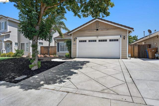 Single-story residence featuring a two-car garage with paneling, a patterned concrete driveway, and a wood fence