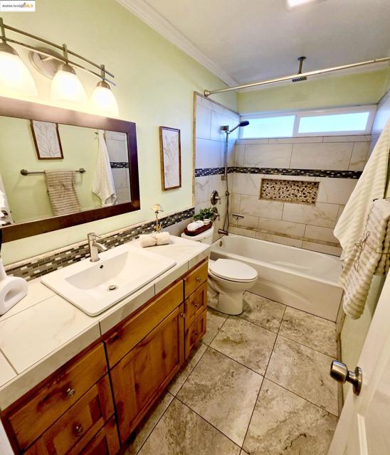 Bathroom with vanity, a combined bath / shower with rainfall shower, light tile patterned floors, and crown molding