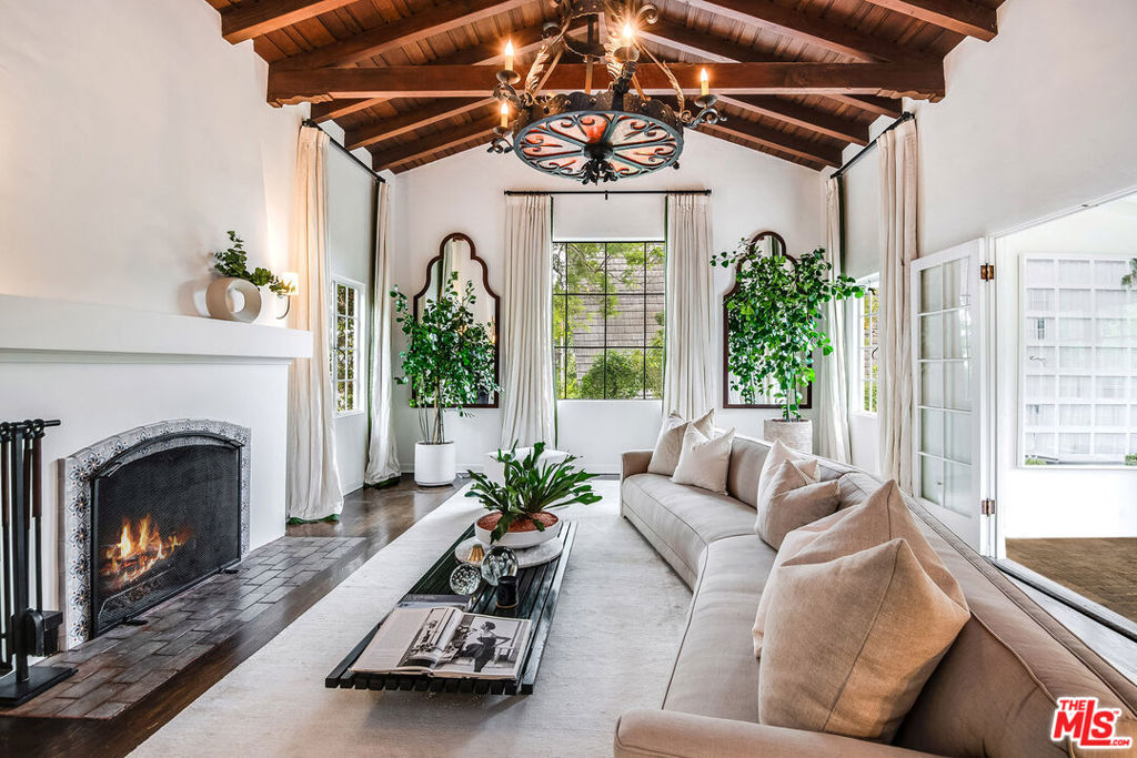 Nestled amidst the lush green hills of the highly sought-after "The Oaks" neighborhood in Los Feliz, this enchanting Spanish dream exudes timeless charm and botanical splendor. As you step through the gates of this vintage beauty, you're greeted by a private and hedged courtyard leading to the formal entry of the home. The heart of this residence is a spectacular living room featuring soaring, exposed-wood beam ceilings, rich wood floors, and a cozy fireplace. Adjacent is a spacious sunroom, bathed in natural light, extending the entire length of the house. A formal dining room, a convenient powder room, and a quaint kitchen with vintage lighting fixtures, an O'keefe and Merritt stove, an inviting breakfast nook, and direct access to a two-car garage complete the first level. Descending to the lower level, you'll discover two generously proportioned guest bedrooms connected by a Jack and Jill bath. The primary suite awaits, offering a well-appointed primary bath, a walk-in closet, and French doors leading to a private lounge deck. Additionally, the bottom level hosts an office, a bathroom, and a laundry room with extra storage. These spaces open up to the breathtaking backyard, an outdoor oasis that has been meticulously enhanced. Mature landscaping, custom stone work, an inviting outdoor dining area, an outdoor kitchen, a firepit circle, and meandering paths that lead to a grassy flat yard create a serene escape. This property offers an abundance of elegant charm, privacy, and botanical beauty, all within one of the most coveted neighborhoods in Los Angeles. Enjoy the convenience of being moments away from restaurants, services, studios, and more, while relishing in the tranquility and sophistication of this Los Feliz gem.
