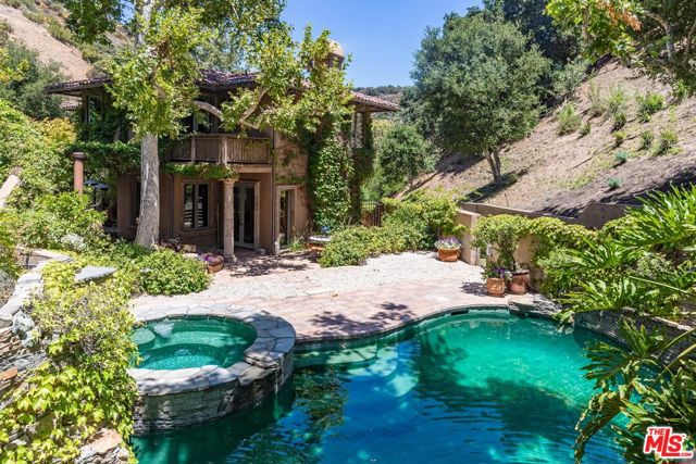13126 Garden Land Road Los Angeles, California Set atop the much coveted Mandeville Canyon, an enchanting estate on almost four acres, brings to mind the romantic villas of the Tuscan countryside. Old World inspiration is readily apparent in its classic barrel-tiled roofline, stately stonework, decorative ironwork, richly hued woods, lush climbing vines, Venetian plaster walls, and earthy terra cotta tile. The heart of the home is an open great room that includes a bright, inviting dining area with sturdy ceiling beams, a living area with an eye-catching fireplace surrounded by built-in bookshelves, and a warm, welcoming kitchen with farmhouse sinks, distinctively detailed wood cabinetry, an oversized island, and stainless-steel appliances including a six-burner Wolf range with a griddle. The colorful billiards room boasts ceiling beams with corbels, a wall of thoughtful built-ins, and a full wet bar. Ideal for more formal moments is an elegant living room with a soaring ceiling, a floating fireplace, and large sun kissed windows. One of four bedrooms, the upstairs owner's suite features a striking pitched beamed ceiling, an expansive walk-in closet, an outdoor patio and an en suite bath with dual vanities and a spa tub tucked away in a windowed corner. Other highlights include an office with double glass doors, a discreet gym with a mirrored wall, and a 200 bottle walk-in wine cellar crafted of stone and wood. Nearly every room on the main level of the residence opens up to the magical grounds. Enjoy alfresco festivities on the cool and breezy covered patio that includes an outdoor kitchen rich with organic hues boasting a built-in stainless-steel grill, a single tap kegerator, and a pizza oven with tile accents. Steps away is an open-air patio flooded with sunlight and a refreshing swimming pool & spa enveloped by dramatic stonework, thriving greenery, and colorful flora. Fenced expanses of manicured grounds and tall trees create the perfect setting for peaceful private wanderings, all just an 8-minute drive from Sunset Boulevard.