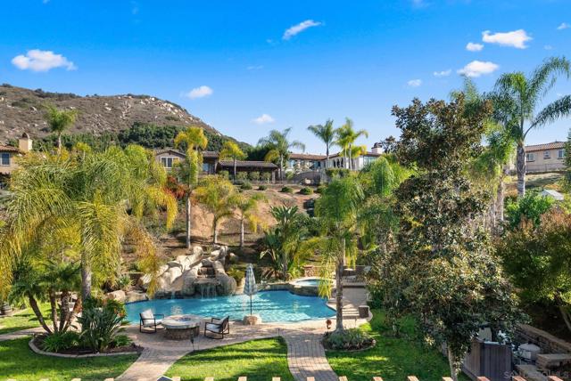 View from Primary Suite covered patio onlooking the luscious mature landscape and entertainers paradise pool and backyard