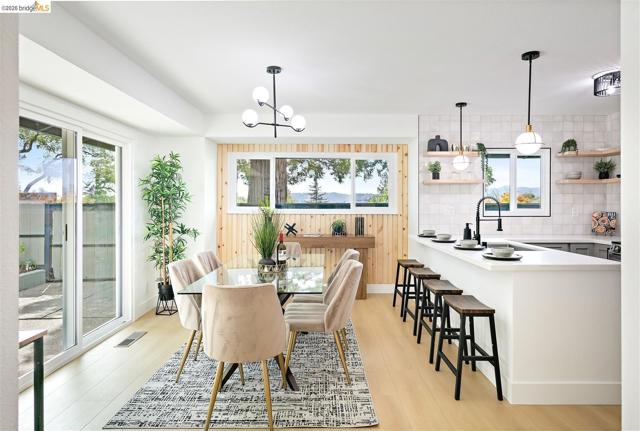 Open-concept dining area featuring wood-finish flooring, a contemporary chandelier, and a sliding glass door to the exterior