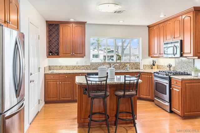 A large kitchen with granite countertops, stainless steel appliances, and a convenient island ideal for cooking and entertaining. Open floor-plan dining area and living room