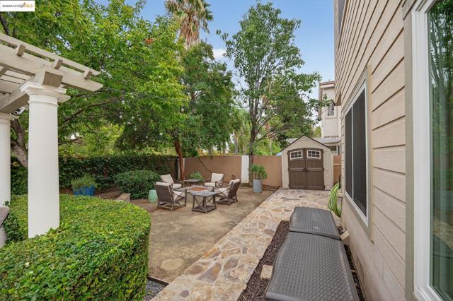 Fenced backyard featuring a patio area, an outdoor fire pit, a storage unit, and a pergola