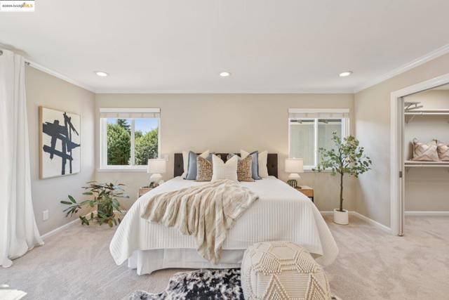 Carpeted bedroom with crown molding, recessed lighting, and a walk in closet