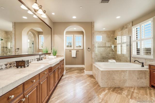 Luxurious dual primary baths with separate spaces. One side features a walk-in shower, vanity, water closet, and walk-in closet. The other offers a large vanity, oversized shower, soaking tub, makeup vanity, water closet, and expansive walk-in closet.