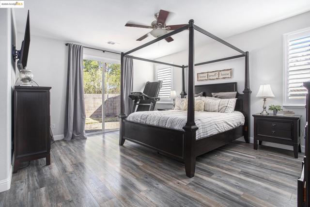 Bedroom featuring access to the exterior, laminate wood finished floors, and a ceiling fan