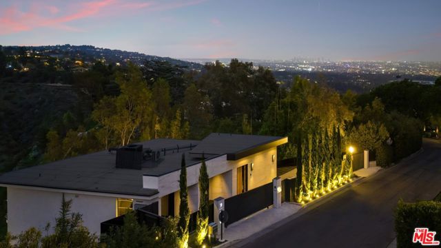 This stunning architectural residence is situated in one of the most highly sought-after locations in Bel Air, offering breathtaking canyon views, pastoral landscapes, and the sparkling city skyline. Recently redesigned and reconstructed, this gated property boasts exceptional privacy, the highest level of craftsmanship and bespoke, contemporary interiors. Immediately greeted by warm Oak and rare, Italian marble - this immaculate home features high ceilings and an open floor plan allowing for head-on views of the panoramic vista from every level. The chef's caliber kitchen is equipped with top-of-the-line Miele appliances, along with custom-made panel Antracita Pearl cabinets that provide ample storage and counter space. The space flows seamlessly into the dining, living area and expansive patio, making it ideal for seamless indoor-outdoor living. Enjoy a martini or watch your favorite sports games from the downstairs full bar and lounge, perfect for all kinds of entertaining. The primary bedroom is a true sanctuary, featuring a chic sitting room and large walk-in closet with Milka system hardware and custom-made laminated panels. The primary bath is equally luxurious, featuring heated floors, a Copper Mosaic shower seat, and bronze mirrors, all adding to the sense of opulence and comfort. Each room is striking, connecting to large terraces overlooking the private pool and spa below - complete with outdoor shower, kitchen and dining for the ultimate retreat under the stars. Other notable amenities include an elevator, which makes moving between floors a breeze, as well as a massage and wellness room for added relaxation. The estate also includes curated artisan detailing, custom fixtures and textures throughout - a true designer's dream with exceptional attention to detail.