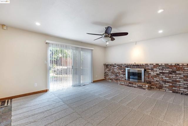 Unfurnished living room featuring carpet floors, a brick fireplace, recessed lighting, ceiling fan, and brick wall