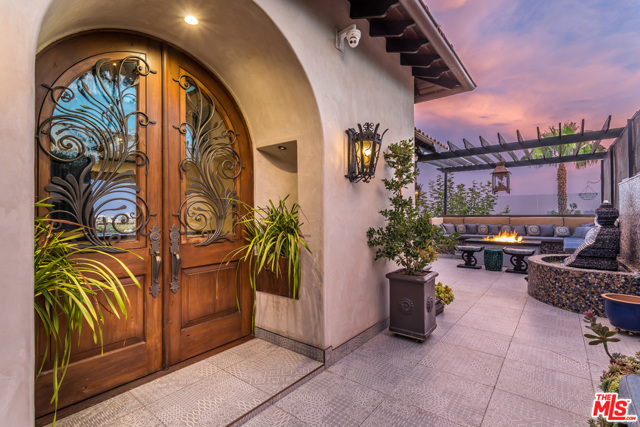 1380 Summitridge Place Beverly Hills, California Elevated above expectations by interior designer Kevin Young, the entire home is wholly unique. From the hand railings infused with rare crystals to the light fixtures and marble countertops, every square inch is completely custom. Three-stories on Beverly Hills Summitridge Drive, the impeccable ensemble of dramatic interiors and nearly 2,000-sq-ft of deck space is an entertainers Eden. A two-screen drop-down projector system enhances the living room for optimal viewing experiences, extending into a top-level deck with a custom water statue, massive gas fire-pit and ample lounging space. Automated blackout curtains unlock your expansive views to the city and ocean while maintaining ultimate privacy. An office with built-in humidor drawers and two master suites with a connecting closet encompass the entirety of the second floor. Pitch perfect sound rooms, a recording studio and barber shop opens to a putting green and pool overlooking the LA cityscape.