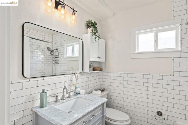 Full bathroom featuring vanity, tile walls, and a tile shower