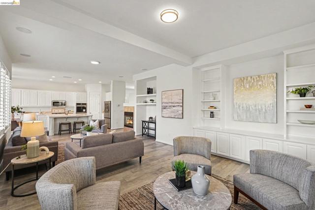 Spacious living area featuring light wood-finish flooring, recessed lighting, and integrated wall shelving with base cabinetry