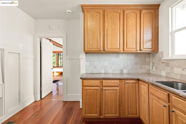 Kitchen featuring healthy amount of natural light, dark stone countertops, dark wood-style floors, and backsplash