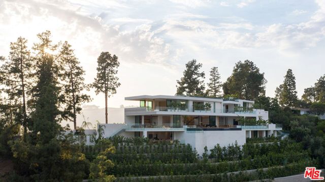1274 Lago Vista Drive Beverly Hills, California Design icon Richard Landry & Merkoh Development joined forces to create this organic modern masterpiece. Located on a very quiet street on a picturesque acre, this showpiece is immersed with spectacular 360 city, ocean & canyon views within the heart of Beverly Hills. Its stunning matchbook travertine exterior and Italian teakwood smart door sets the tone for an elegant mix of serenity-evoking aesthetics and cutting-edge automated lifestyle. Interiors feature world-class Italian Classico unfilled travertine, teakwood, white oak louvers & floorings throughout. Beautiful open floor plan with soaring motorized sliding doors soaks up the sunlight and the explosive views. Tri-level entertainment oasis with 2 exquisite bars & kitchens, formal & alfresco dining options, a movie theater, sauna/steam, gym & wine rooms. Gourmet Kitchen features servo cabinetry & calacatta viola countertop bar. Multiple decks, perfect for entertaining on any scale boast BBQ kitchen, rooftop jacuzzi, rooftop yoga