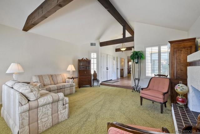 Wood-beamed, high ceilings give this living room a Santa Barbara feel.  Gas fireplace and raised hearth and abundant windows.