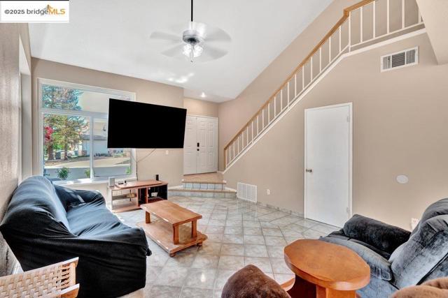 Living area featuring a ceiling fan and stairs