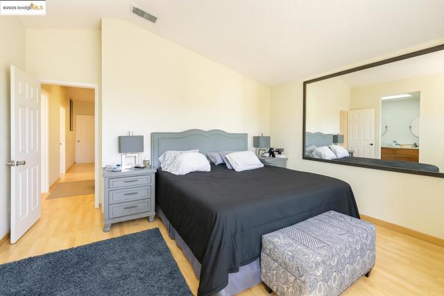 Bedroom with light wood finished floors and lofted ceiling