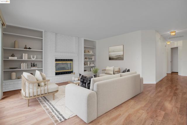 Living area featuring a fireplace, light wood finished floors, and built in shelves