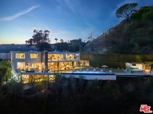 A spectacular contemporary estate built in 2015 sets the tone for luxury living in Bel Air. The open floor plan with high ceilings and grand scale is perfect for entertaining. The expansive and meticulous landscaped lawn and outdoor entertainment area is the perfect setting for enjoying the Southern California lifestyle. Surrounding canyon and ocean views offer a level of tranquility and the utmost privacy unlike any other. Featuring a family room, den, gym, four fireplaces, elevator, 300-bottle glass wine cellar, and a state-of-the-art home theater with en-suite bar. 5 bedrooms on the upper floor all with views and 2 additional bedrooms on the lower level perfect for staff, gym, recording studio, offices or game rooms.  Incredibly private on a promontory overlooking the rolling hills of Beverly Hills and Beverly Crest neighborhoods and hidden behind huge ficus hedges in the front. Indoor/outdoor living has been optimized with automated retractable walls of glass, outdoor kitchen and bar, and an infinity pool and spa. This is an opportunity to own a significant piece of architecture with unparalleled quality.