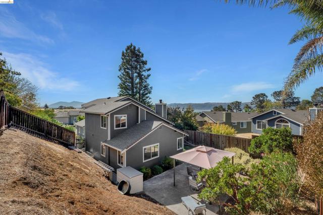 Contemporary exterior siding, sloped backyard, concrete patio, mature landscaping, wood fencing