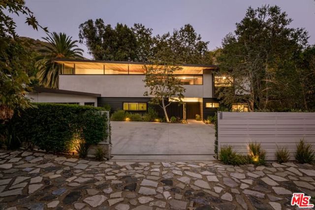 2496 Mandeville Canyon Road Los Angeles, California This Mandeville Canyon study of modernism represents the collaboration between its owners and architect Jesse Bornstein, AIA. References to L. A. s great modernists like A. Quincy Jones flow throughout as Bornstein used the spectacular site and its tree-shrouded surrounds as inspiration for the custom gated compound. The sustainable property encompasses a 4 bedroom, 3.5 bath main house with an office, den, gym, and a guest house with bath, pool and spa amid an arrestingly tranquil xeriscape. Timeless and natural materials such as polished concrete, ribbons of black aluminum, gypsum plaster and a rich mix of woods like Walnut and California Redwood blend with all manner and form of glass -clear, tinted, clerestory and retractable sliding folding doors creating dramatic, expansive, highly livable space that seamlessly interacts with the natural landscape and light. The two-story floorplan opens at its center into a gorgeous, broad living room and dining space with 20-foot ceilings, granite double-sided fireplace and walls of glass opening to nature. A superb gourmet kitchen with center island unfolds into the family room. An office, guest suite, utility room and powder bath complete the first level. An open broad-lit wide stairwell leads to a mezzanine open to below and gorgeous vistas beyond as the second level continues to balance proportion, light and a visual relationship to nature. The spacious primary suite rests in its own wing with a fireplace, generous his/her closet, and set behind exotic Shoji glass movable panels, a Zen bath with double vanities, spa tub and shower. Adjoining the primary suite is a gym and private patio with verdant overlook. The opposite wing contains an open den plus two spacious guest bedrooms with full bath. A canvas of custom details enhances the entire living space indirect recessed and modern lighting fixtures, Brazilian black granite, Pennsylvania flagstone, built-in speakers, shelving and seating, plus a security system, 6-zone HVAC, laundry chute, green low VOC paint, filtration at kitchen and pool house sinks, copper ion filtration at pool and much more. A large motorcourt for 7+ cars extends the 3-car direct garage space. A rare architectural find in prime Brentwood, completely congruent with its sublime setting.