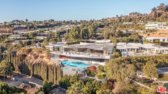 Located on the most prestigious cul-de-sac in the famed Trousdale Estates, this remarkable multi-level home offers a phenomenal opportunity to own or develop one of the most unique properties in all of Los Angeles. This one-of-a-kind estate was built down more than 80 feet deep into a steep hillside, allowing for a multi-level home that takes full advantage of unobstructed panoramic south-facing views spanning from Downtown to the Pacific Ocean.  The house sits on half an acre, features 5 bedrooms and 7 bathrooms, and includes expansive entertainers' terraces, a pool, and an indoor racquetball court. Plans for a new architectural masterpiece designed by award-winning architect Michele Saee, AIA, are available with the purchase. The new design nicknamed The Butterfly House for its unique wing-shaped roof resembling the contour of a butterfly was inspired by the idea of flight and a sense of floating above LA. The concept builds on the grandfathered-in structure plus a new proposed basement apx 7,990 sq.ft. pending conceptual approval for a total allowable 18,000 sq.ft. home.  Walls of glass and distinctive skylights on the rippling roof line above allow an abundance of light into the interior of the home. An open floor plan on the main level includes a great room, kitchen and dining room and several wings that lead to separate sleeping quarters, guest rooms and a library. An expanded lower level features a movie-theatre, game room, a gym with steam and sauna, underground parking garage and two additional suites with access to the relocated pool and spa. From the first visit, this home will capture your imagination. A truly once in a lifetime opportunity to own a unique property that can never be duplicated.