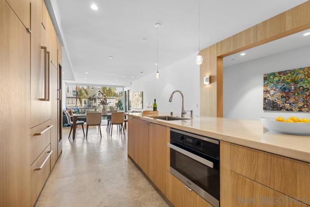 Kitchen island features Macaubus quartzite granite countertops with built in Miele microwave and stainless steel sink.