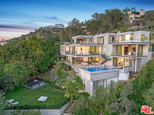 Located in the prestigious Crest Streets in Beverly Hills, this architectural masterpiece offers unobstructed jetliner views from every room. The new construction smart house features Venetian wall finishes throughout, imported stonework, floor-to-ceiling walls and doors of glass, and over 3,400 sq. ft. of outdoor terraces, creating an unprecedented living experience. The 2,000 sq. ft. primary suite boasts a private glam room, hair salon, 2 garden lounge sitting areas, dual walk-in closets, wet bar, and glass shoe display room. The gourmet kitchen comes replete with a butler kitchen and pantry area. The sophisticated living and dining area is accentuated with a fingerprint-secured Mezcal/Wine tasting room. The lower entertainment level offers a luxurious bar, spa and theatre experience, including a zero-edge pool, Himalayan salt sauna, Japanese soaking tub, private yoga studio/gym, Tonal fitness system, wet steam room, poolside cabana room, and 20 person theater with bar. The private lower grassy yard is surrounded by lush landscaping and includes a large entertainment game space.