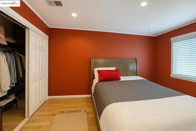 Bedroom featuring light wood-style flooring, crown molding, recessed lighting, and a closet