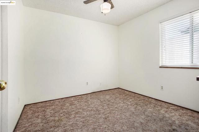 Carpeted empty room featuring a textured ceiling and a ceiling fan