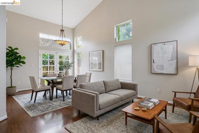 Vaulted ceilings, dark wood-finish flooring, French doors, multiple windows, and a chandelier with glass shades