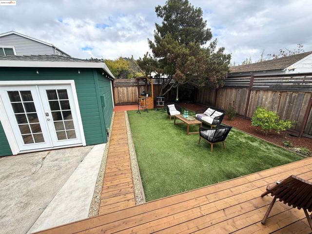 Fenced backyard with a wooden deck, french doors, and outdoor lounge area