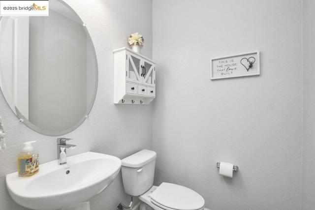 Half bath with a textured wall and toilet