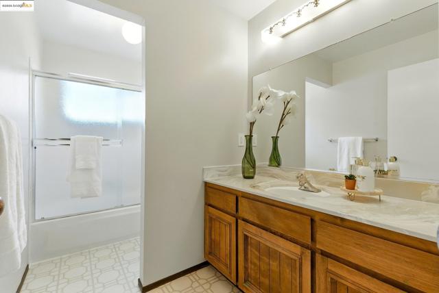 Full bathroom with tile patterned floors, vanity, and bath / shower combo with glass door