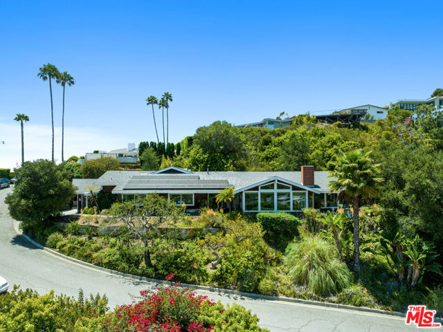 With panoramic ocean and mountain views, this single level, Mid-Century modern property is your own slice of paradise! The spacious public rooms have a slate entrance and wood floors, high ceilings and expansive windows providing glorious views and extraordinary light. At night, marvel at the sparkling lights of Santa Monica Bay and the Palos Verdes peninsula.  The dining area with open beamed ceiling flows into a secluded  grassy yard and dining patio facing the ocean.  The living room with wood burning fireplace has wraparound views. The updated kitchen includes built-in stainless double ovens, refrigerator/freezer with water and ice dispenser, and a separate wine refrigerator. There is a breakfast bar in addition to a breakfast room area. The primary bedroom suite opens to the rear yard and terraced hillside garden and includes 2 walk-in closets and a sumptuous bath. One guest bedroom has its own bath. The second guest bedroom, currently being used as an office with built-in desk, shelves and cabinetry, and the large front den/office, both with ocean views, share a bath. The laundry area is in the attached garage with direct entry.